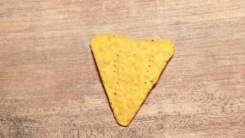 One yellow triangular nachos are eaten stop motion timelapse. Fast food and high-calorie food. Chips for snacking