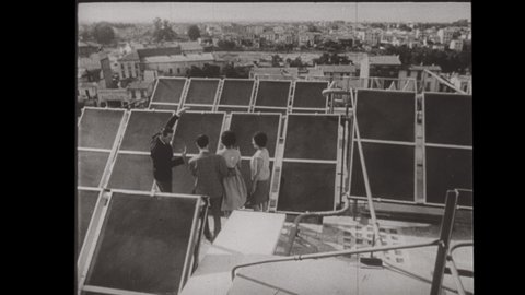 1950's Paris France. A Hotel utilizes Solar Panels and Geo-Thermal Energy to produce Energy. A Couple Inspects Solar Panels on the Roof of a Hotel. 4K Scan of Archival 16mm Film