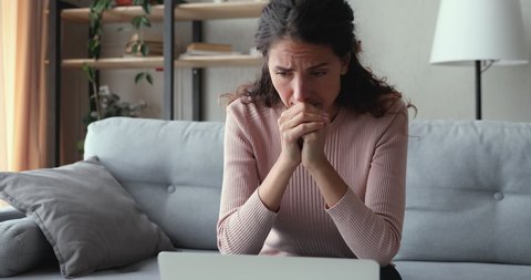 Worried young adult woman looking at laptop feeling frustrated desperate reading bad negative online news sitting at home. Stressed upset female user using computer anxious about financial problems.