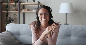 Happy young business woman wears headset talks to web camera making distance online video conference call. Female internet teacher doing distant chat working from home. Telework concept. Webcam view
