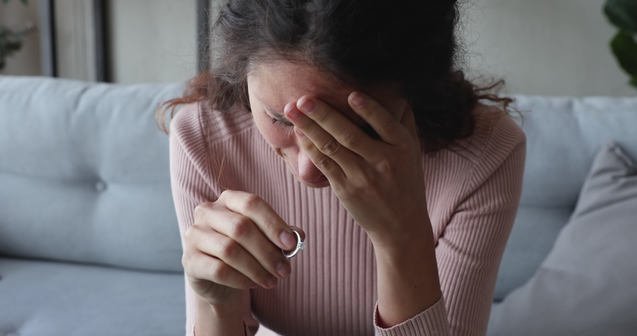 Depressed disappointed young woman taking off wedding engagement ring regrets unhappy marriage mistake. Upset frustrated wife thinking of divorce makes difficult decision about break up. Close up view | Shutterstock HD Video #1049471845