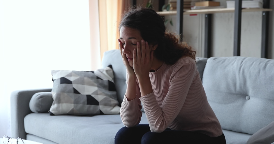 Worried upset young woman sitting on sofa anxious about problem, suffers from mental stress, regrets mistake. Depressed girl thinking of loneliness, feels guilt, makes difficult decision concept. | Shutterstock HD Video #1049471872