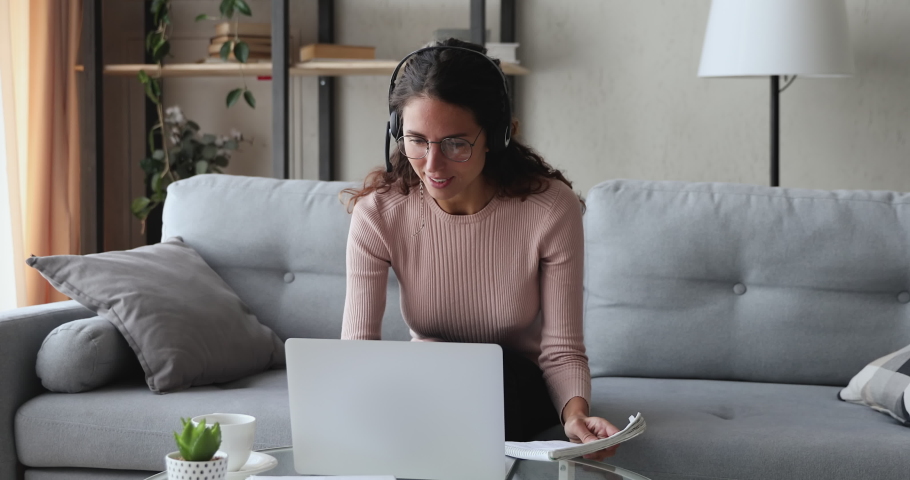 Young woman wears headset conference calling on laptop talks with online teacher studying, working from home. Lady student e learning using computer webcam chat makes notes. Distance education concept Royalty-Free Stock Footage #1049471893