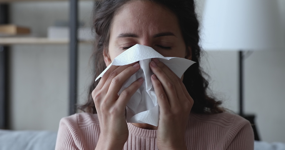 Ill sick young woman sneezing in tissue, blowing runny nose. Millennial lady having flu coronavirus cold symptoms at home. Covid 19 virus infection, flu and seasonal allergy concept. Close up view Royalty-Free Stock Footage #1049471908