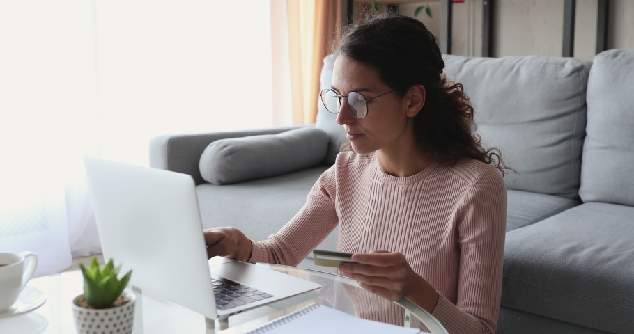 Young woman customer doing internet shopping holding credit card makes retail purchase secure online payment concept typing on laptop at home. Millennial shopper paying on website ordering delivery. Royalty-Free Stock Footage #1049471917