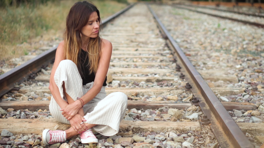 Sad young woman sitting on the railway .
