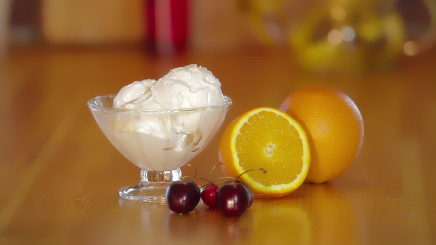Sweet summer dessert. Ice cream in glass bowl with walnut. Orange and cherry on a wooden table. Preparation of ice cream gelato. Sweet cold dessert.