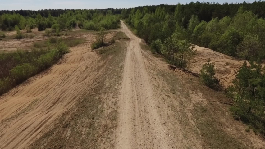 Slow-motion video of a man riding a yellow quad bike, and speeding off into the distance, leaving behind a cloud of dirt and dust