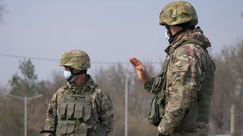 Almaty, Kazakhstan - March 20, 2020: Two soldiers in medical masks pass cars at a checkpoint during a coronavirus