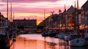 Copenhagen, Denmark. Time-lapse at sunset. View of famous Nyhavn area in the center of Copenhagen, Denmark. Various boats moored with historical buildings and cloudy sunset bright sky, panning video