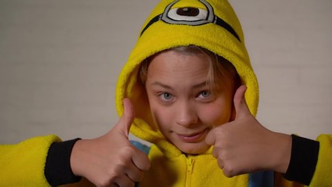 Chernihiv, Ukraine - January 16, 2020: Closeup view video portrait of cute happy funny kid dressed in blue and yellow minion costume dancing cheerfully, making silly faces and showing two thumbs up.