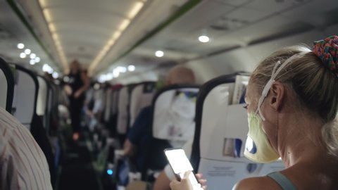 Woman travel tourist caucasian at plane aircraft with wearing protective medical mask. Read shock news about coronovirus at smartphone mobile. Virus coronavirus epidemic sars-cov-2 covid-19 2019-ncov.