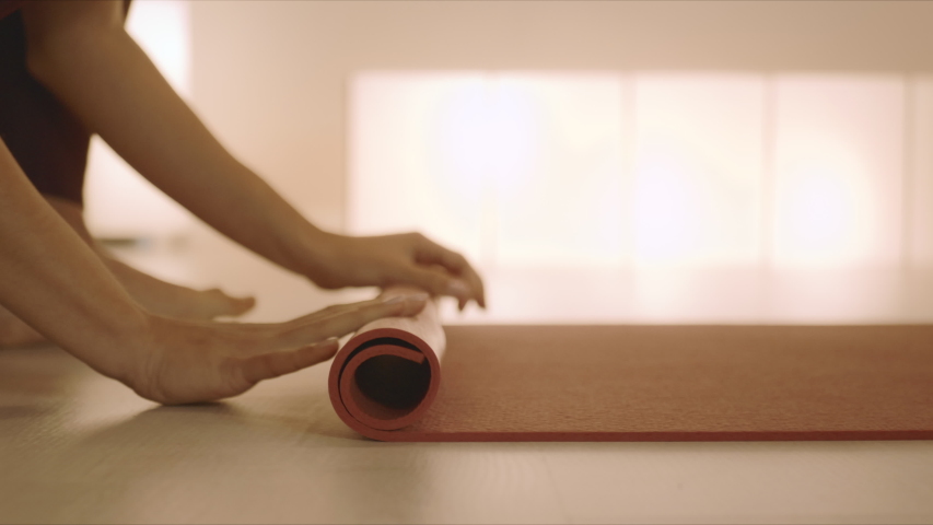 Closeup woman hands rolling up yoga mat after training in studio. Unrecognizable barefoot girl folding fitness mat on floor at yoga studio in slow motion Royalty-Free Stock Footage #1049507245