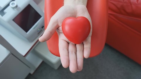 Red rubber heart in a hand. Man hand is donating venous blood. Gripping squeezing stress ball. Blood donation concept 4k