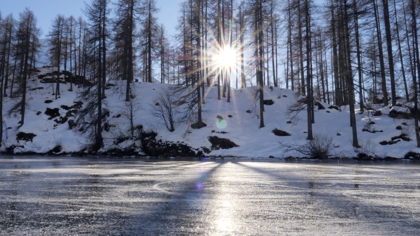 Young woman ice skating on frozen lake in winter. Female on ice skates surrounded by stunning mountain landscape. Natural frozen lake in the Alps. Woman enjoying winter season 