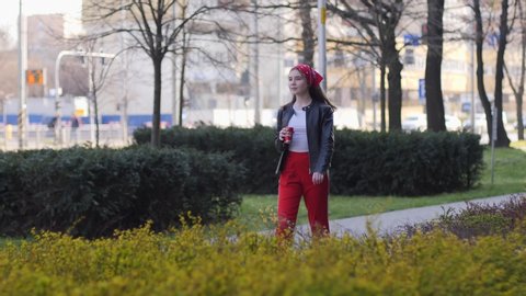 WROCLAW, POLAND - MAR 29, 2020: Teenager kid girl drinks coca cola carbonated can beverage walking outdoors on city street sidewalk