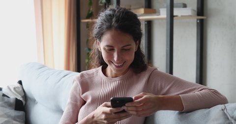 Smiling young woman using voice recognition assistant on smartphone at home. Happy lady records audio message, talking on mobile speakerphone, commands digital ai assistance app online search concept.