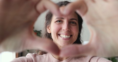 Smiling young woman volunteer showing hands sign heart shape looking at camera. Healthy heart health life insurance, love and charity, voluntary social work, organ donation concept, close up portrait.