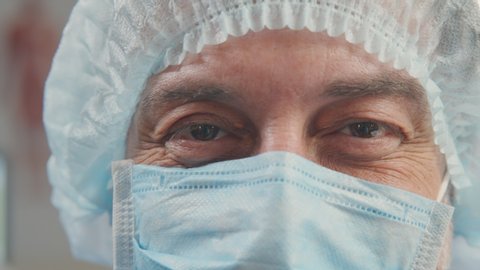 Close-up portrait of tired exhausted doctor with mask and headset after hard shift and treating patients in hospital or clinic. Practitioner or surgeon smiling behind medical mask. Concept of medicine