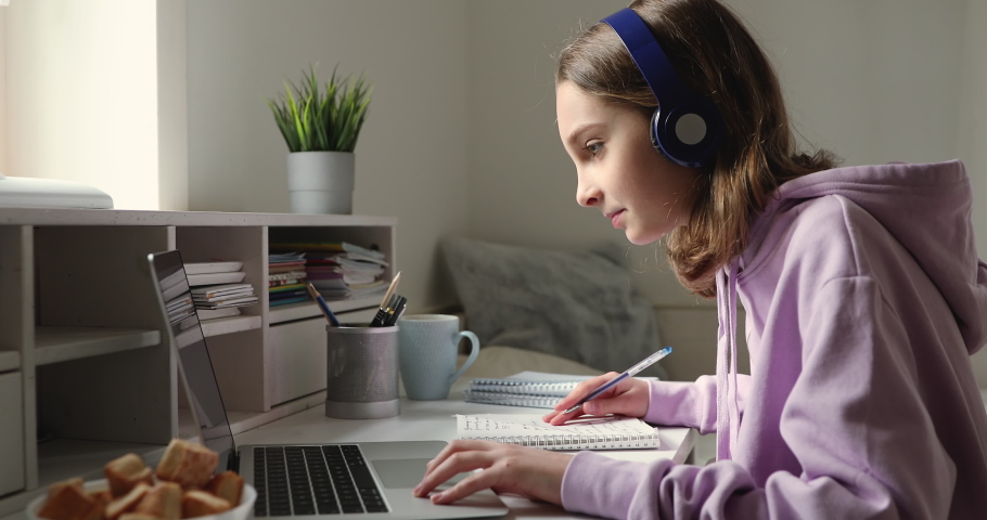 Teenage girl wearing headphones studying online from home with distance teacher. Teen school student distance learning in internet making notes, doing homework, watching video tutorial course concept. Royalty-Free Stock Footage #1049543284