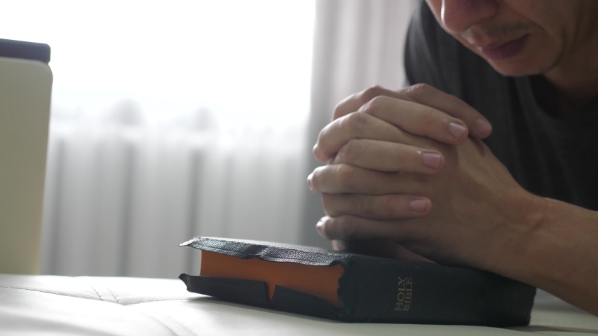 man praying indoors at bedtime on bible. lifestyle religion concept evening prayer human brunette hands on bible praying by bed Royalty-Free Stock Footage #1049547943