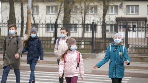 School children cross the road in medical masks. Children go to school