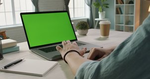 Close up shot of hands of freelancer working with chroma key green screen laptop, using trackpad scrolling through website - technology concept 4k video template