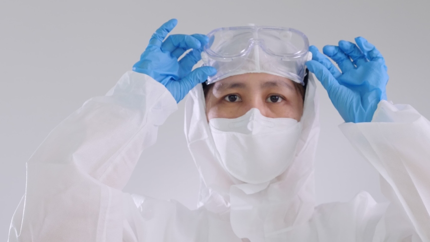 Asian doctor in protective hazmat PPE suit wearing face mask and eyeglasses, Slow motion  shot Royalty-Free Stock Footage #1049561782