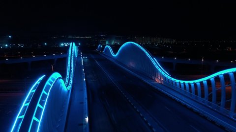 Empty futuristic bridge in Dubai at night. Blue neon light. 4K aerial footage. Modern city concept. 