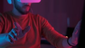 Handsome man wearing virtual reality headset. Closeup hand movements. Augmented Reality. Student developer touch something using modern 3D vr glasses indoors with colourful neon lights. Future is now - Powered by Shutterstock - Get 15% off with code: PIKWIZARD15