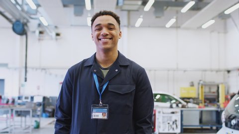 Portrait of male student studying for auto mechanic apprenticeship at college smiling at camera - shot in slow motion