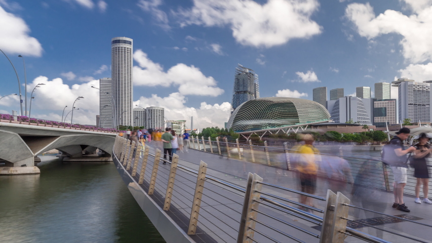 Esplanade Theatres domes behind Esplanade bridge near Esplanade Drive with traffic timelapse hyperlapse. Singapore skyscrapers skyline on a background