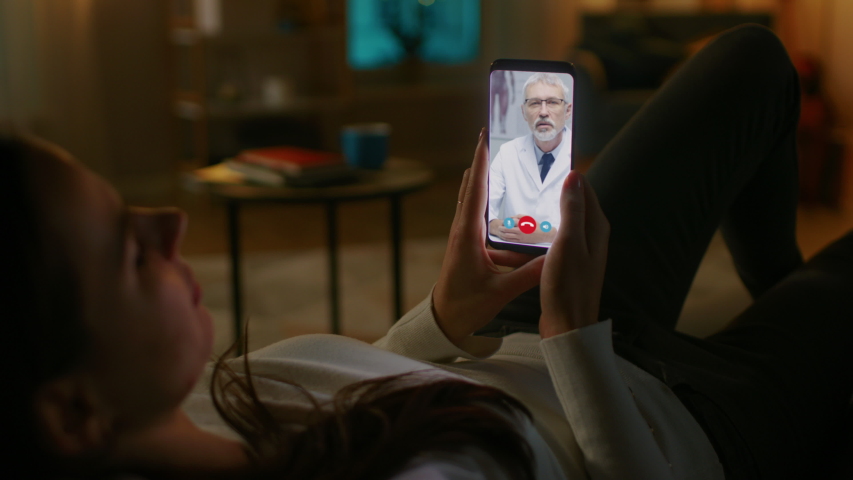 Young Girl Sick at Home Using Smartphone to Talk to Her Doctor via Video Conference Medical App. Woman Has Conversation with Professional Physician, Using Online Video Chat Application. Late at Night | Shutterstock HD Video #1049595025