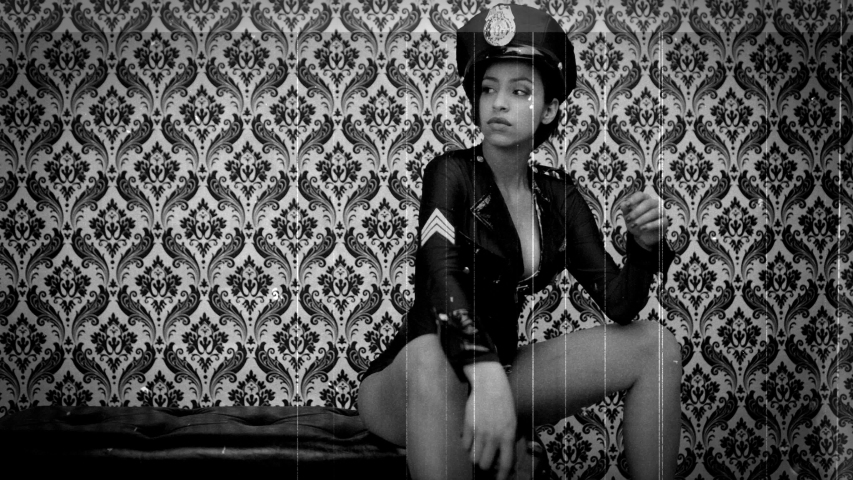 Scratched celluloid film of a young woman wearing police hat and uniform sitting holding weapon and dancing.