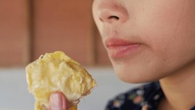 Slow-motion video of a woman eating durian with deliciousness.