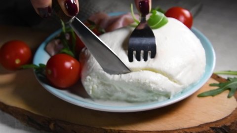 the hands cutting a big fresh mozzarella cheese, food made in Puglia, Italy, regional cuisine, close up, slow motion