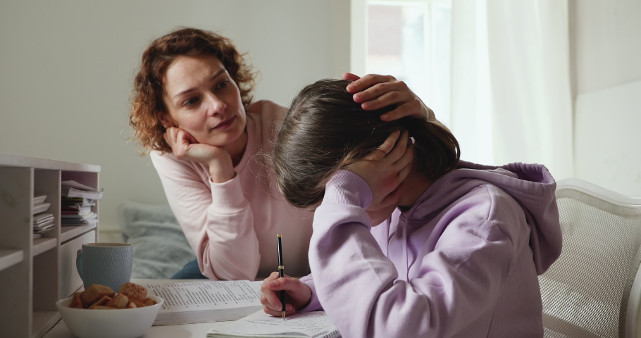 Caring young parent mom supporting tired upset teen school child daughter having difficulty with education learning at home. Mum comforting sad teenage girl encouraging helping with studies concept. | Shutterstock HD Video #1049601547