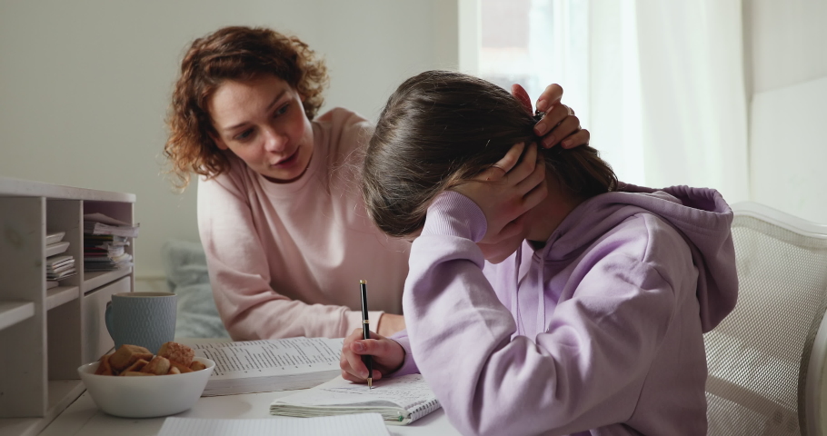 Caring young parent mom supporting tired upset teen school child daughter having difficulty with education learning at home. Mum comforting sad teenage girl encouraging helping with studies concept.