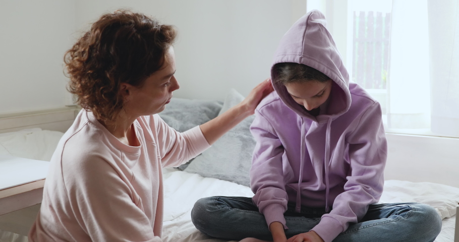 Caring single mother helping sensitive depressed teenage daughter after divorce concept. Affectionate worried young mom apologizing upset teen child girl giving love protection, psychological support. | Shutterstock HD Video #1049601592