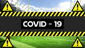 Animation of the word Covid-19 written in black letters on yellow and black tape with four black yellow warning triangles over a rugby stadium in the background. Medicine sport public health pandemic - Powered by Shutterstock - Get 15% off with code: PIKWIZARD15
