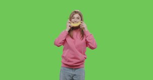 Young pretty girl making fun with banana isolated over green screen background. Chroma key. 4k raw video footage slow motion