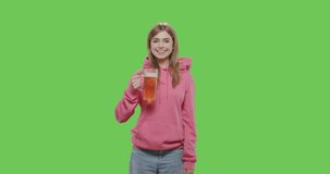 Pretty young woman drinking beer from the glass. isolated over green screen background. Girl making thumbs up on chroma key. 4k raw video footage slow motion