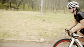 Sporty woman riding bicycle. Side view of athletic woman in sportswear cycling on bike in park, tracking shot. Cycling concept