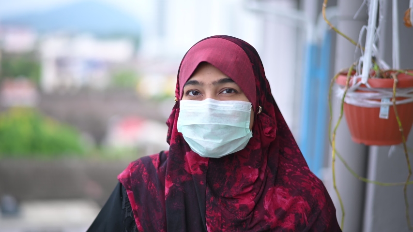 Coronavirus and Air pollution pm2.5 concept. young beautiful Muslim woman in medical mask,looking at camera. Health care and medical concept.  | Shutterstock HD Video #1049628988