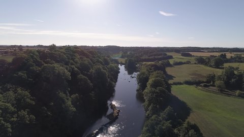 Aerial shot above the river tees following the river through the countryside on a sunny day.