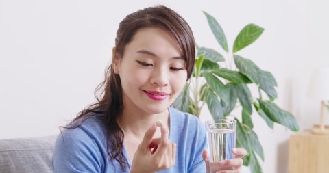 asian woman eat medicine pills to increase immunity with water and feel better at home