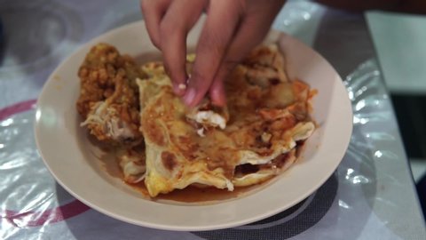 A boy eating Roti Canai, a famous breakfast food in Malaysia in a plate on the table.