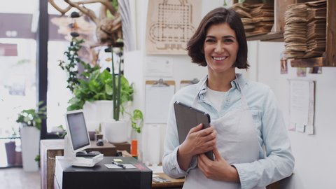 Portrait of female owner of florists shop working on digital tablet behind sales desk - shot in slow motion - Βίντεο στοκ