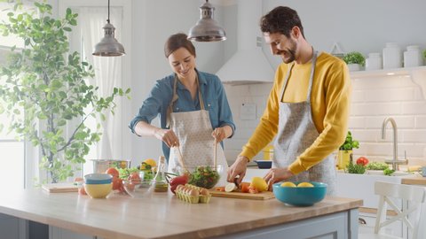 In Kitchen: Perfectly Happy Couple Preparing Healthy Food, Lots of Vegetables. Man Juggles with Fruits, Makes Her Girlfriend Laugh. Lovely People in Love Have Fun