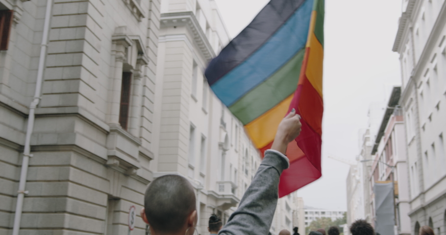 Rear view of people in a gay pride march. Woman holding a rainbow flag in a gay parade in the city.
 Royalty-Free Stock Footage #1049666176